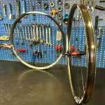 Coppia diRuote artigianali spacebikes appoggiate su un banco da lavoro