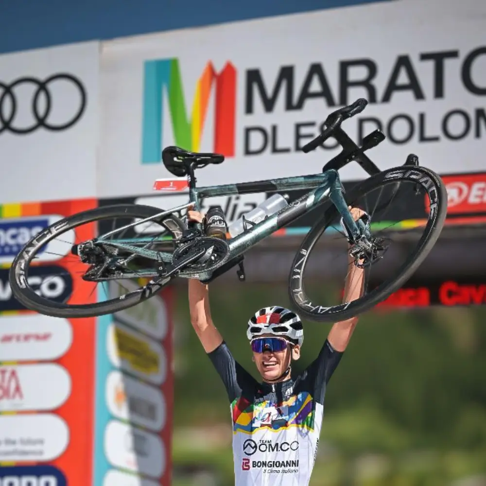 Vincitore maratona dles dolomites 2026 che alza in aria la sua bici con ruote space carbon