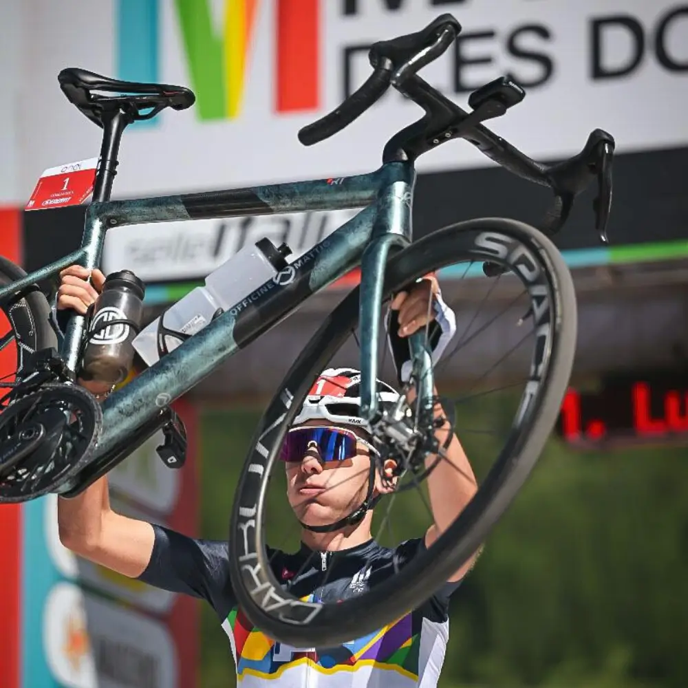 atleta che solleva una bici con ruote in carbonio